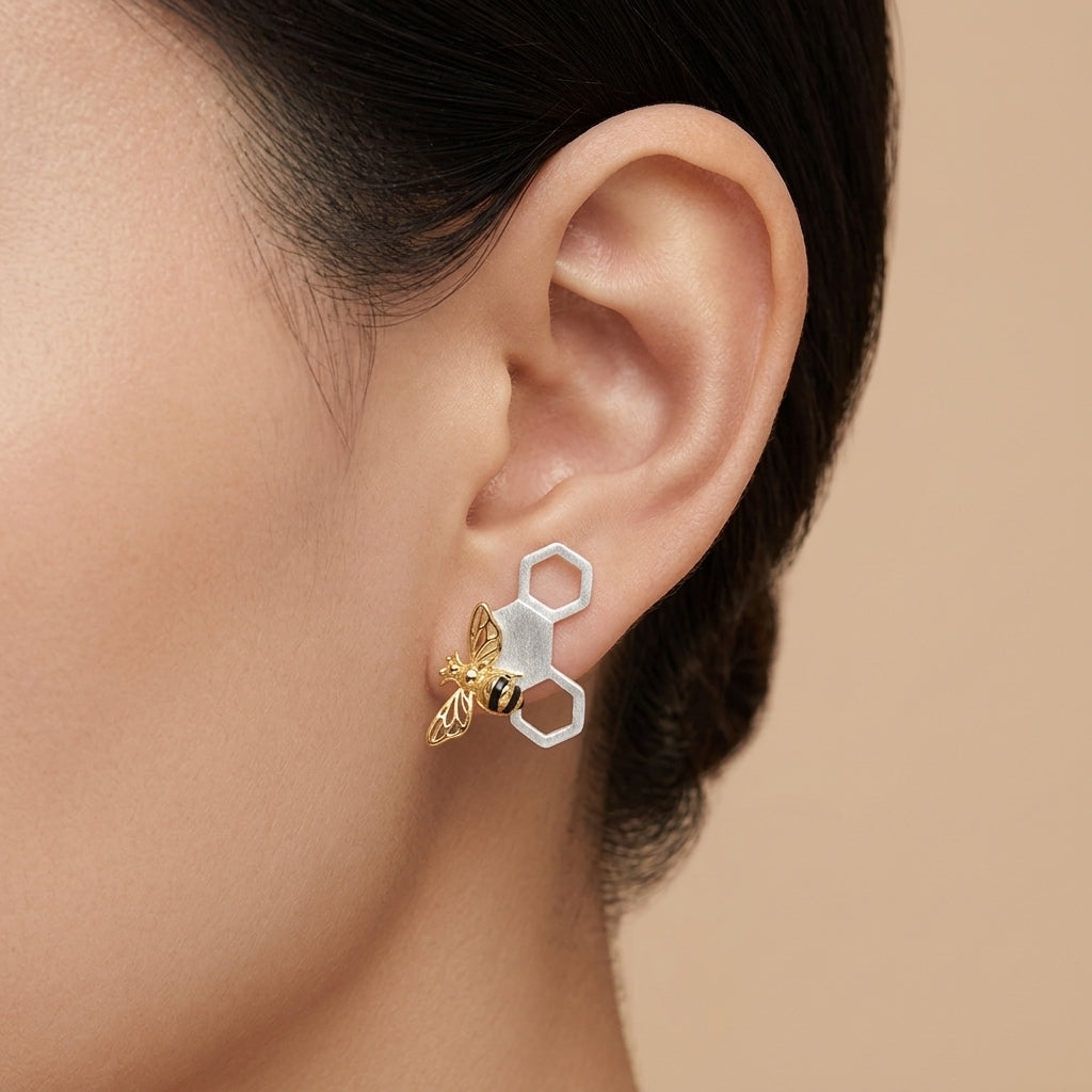 Mismatched bee and honeycomb stud earrings with sculpted bees and geometric comb patterns set at different positions