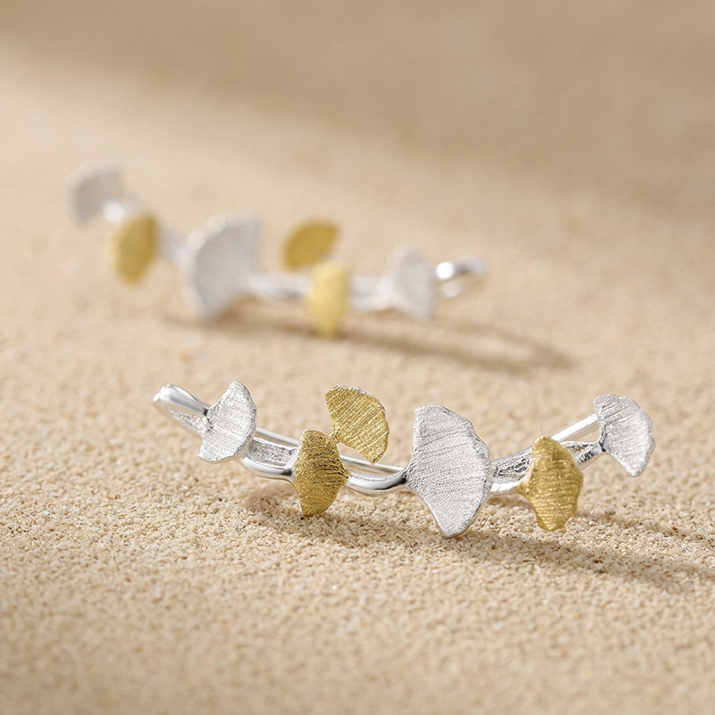 Minimalist 18kt gold plated ginkgo leaf ear climbers styled for a modern, high-fashion aesthetic