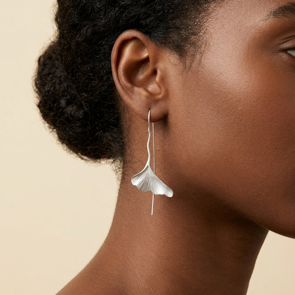 Model wearing long silver Ginkgo leaf earrings showing the delicate botanical texture and hook style
