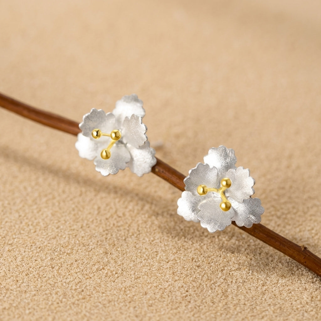 Dainty floral stud earrings in sterling silver finish with textured petals and 18k gold-plated center stamens