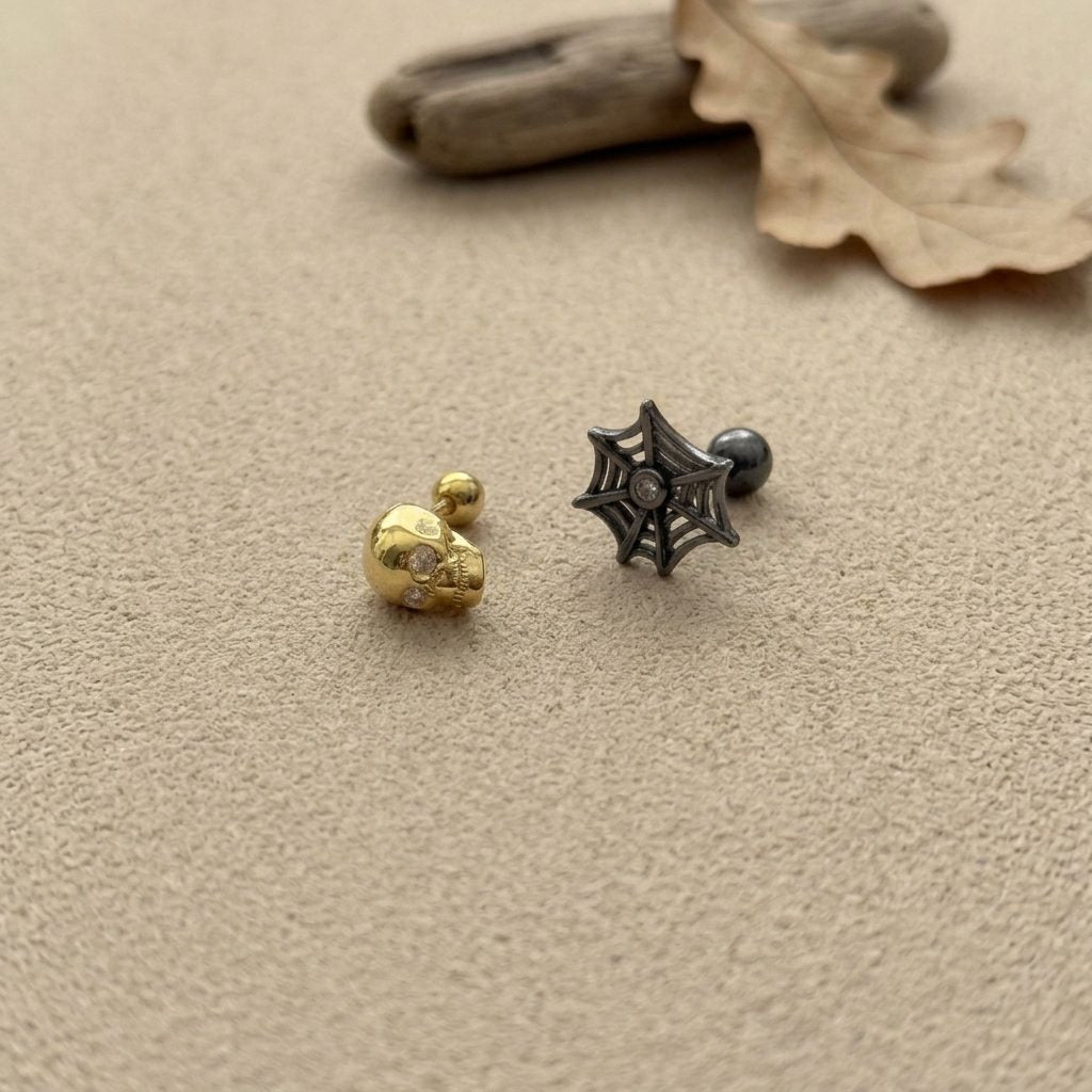 3D skull and spiderweb cartilage stud earrings in gold and black oxidized finish