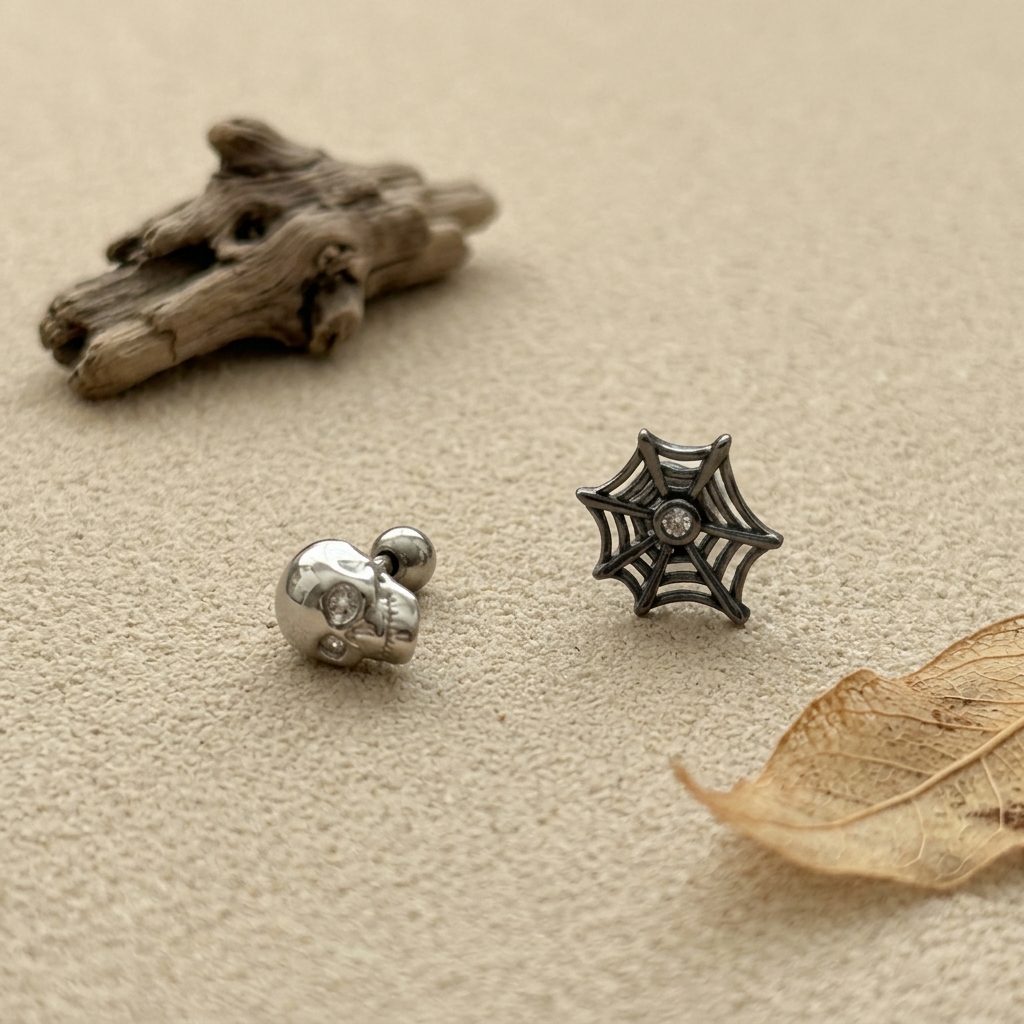 Sculpted silver skull and black spiderweb stud earrings with sparkling stone accents
