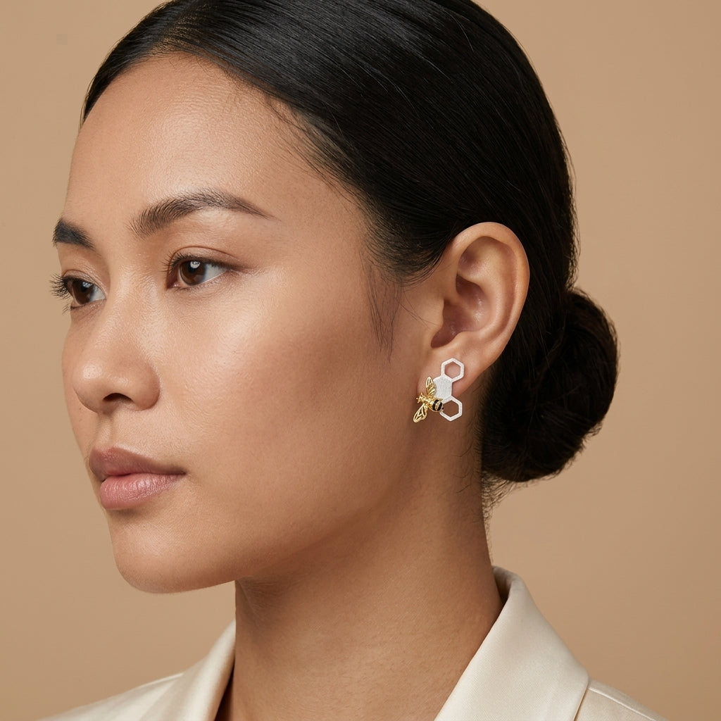 Model wearing 18kt gold bee and comb earrings to show scale and how the nature-inspired design sits on the earlobe