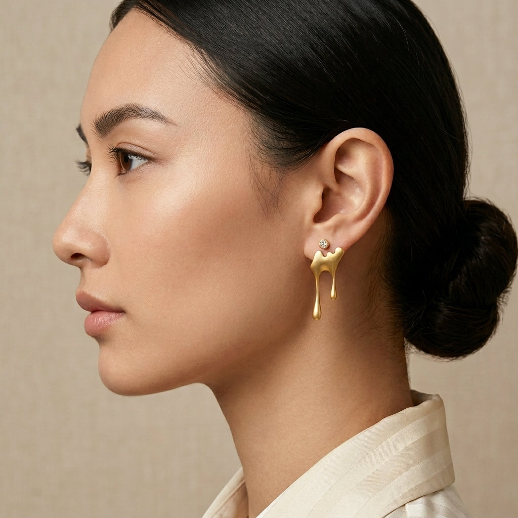 Detailed view of the 18kt gold honey drip earring, featuring a smooth, liquid-metal aesthetic in a mismatched earring style