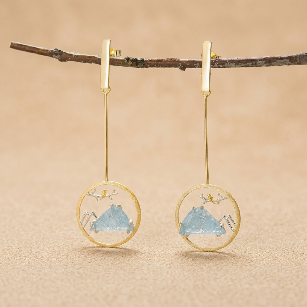 18kt gold-plated sterling silver circular dangle earrings featuring a delicate bird on a branch with a scenic mountain backdrop