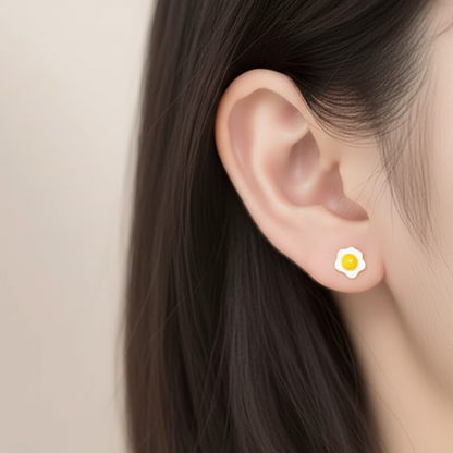 Close-up of a model wearing a petite fried egg stud earring in sterling silver and yellow enamel.