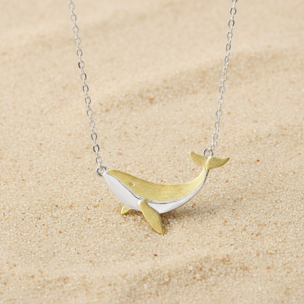 Elegant sterling silver whale necklace with gold accents, styled as a dainty nautical accessory for summer or ocean lovers.
