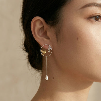 Handcrafted Humming Bird dangle earrings in 18kt gold plating and sterling silver, featuring a delicate bird hovering near a leaf