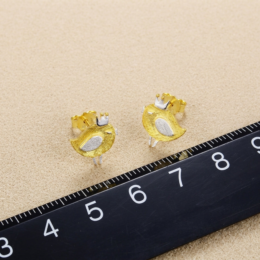 Side profile of a model wearing tiny 18kt gold bird studs to demonstrate the dainty scale and comfortable fit on the earlobe