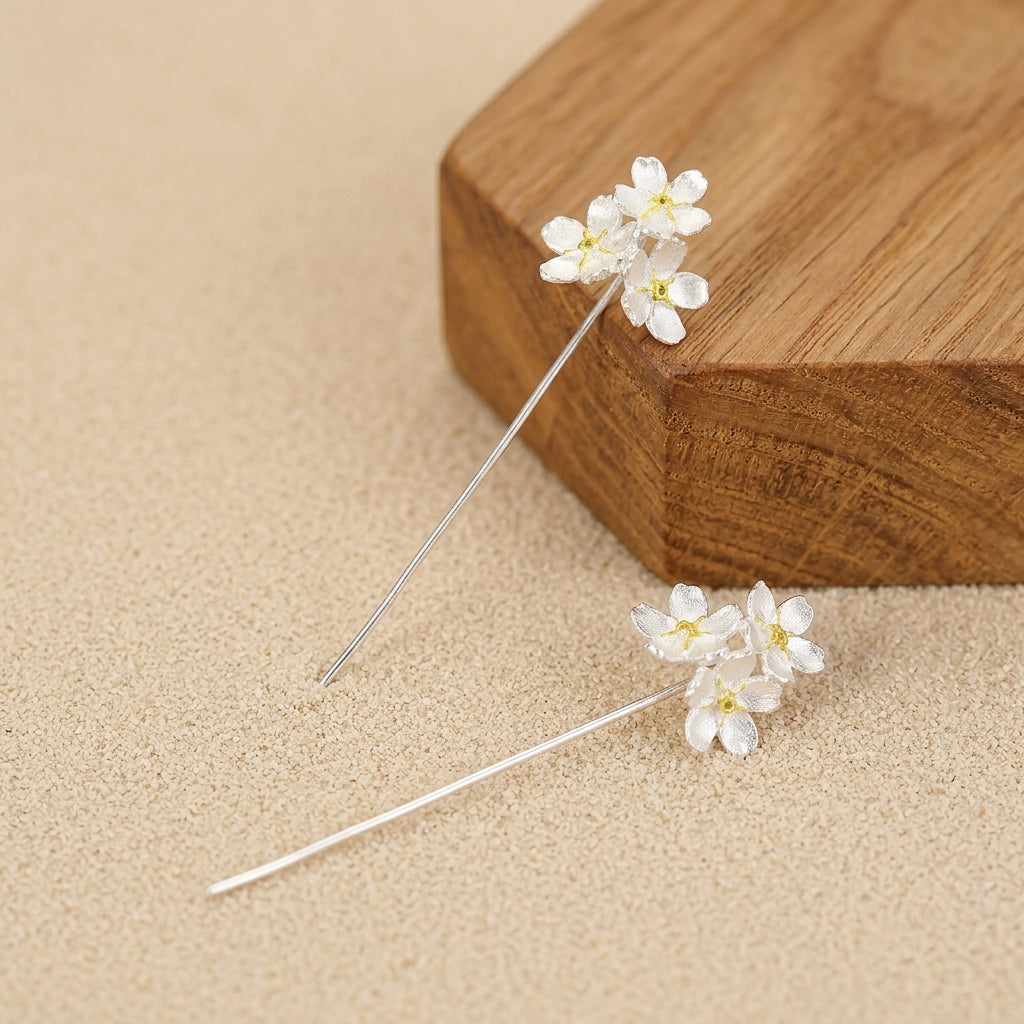 Sterling silver stud dangle earrings featuring three delicate flowers with gold plated accents in a vertical drop design.