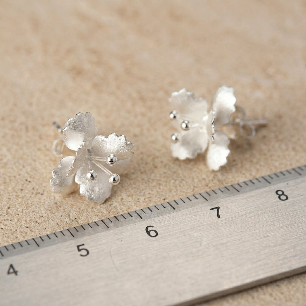 Macro shot of 3D botanical flower earrings in polished sterling silver with hand-finished 18kt gold accents